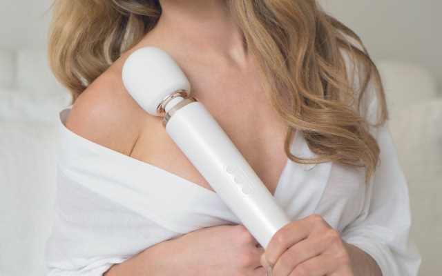 Woman holding wand vibrator Blonde woman in white top holding up a white wand vibrator